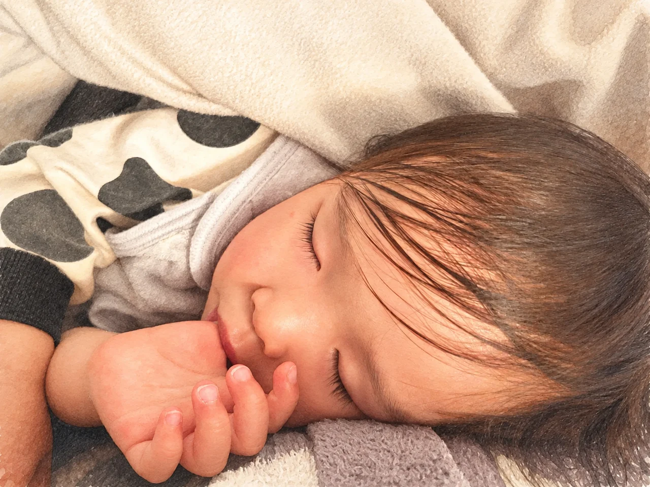 目を閉じている子どもの顔と、口元の手。わが家の写真を淡いイラスト調に加工